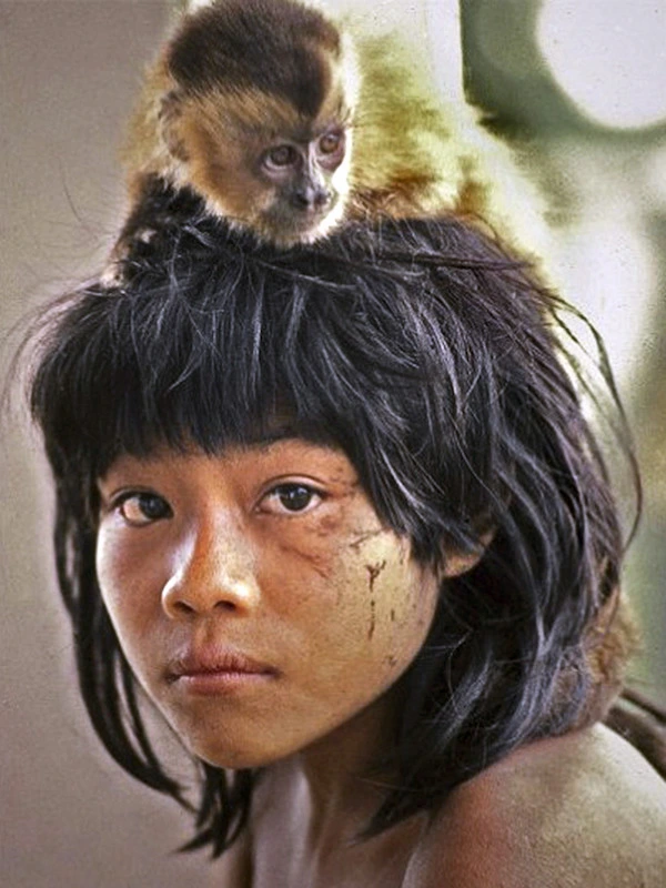 Criança Avá-Canoeiro em fotografia antiga, com um pequeno macaco sobre o cabelo